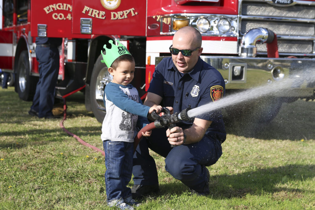 Fireman showing a kid how to hold a hose