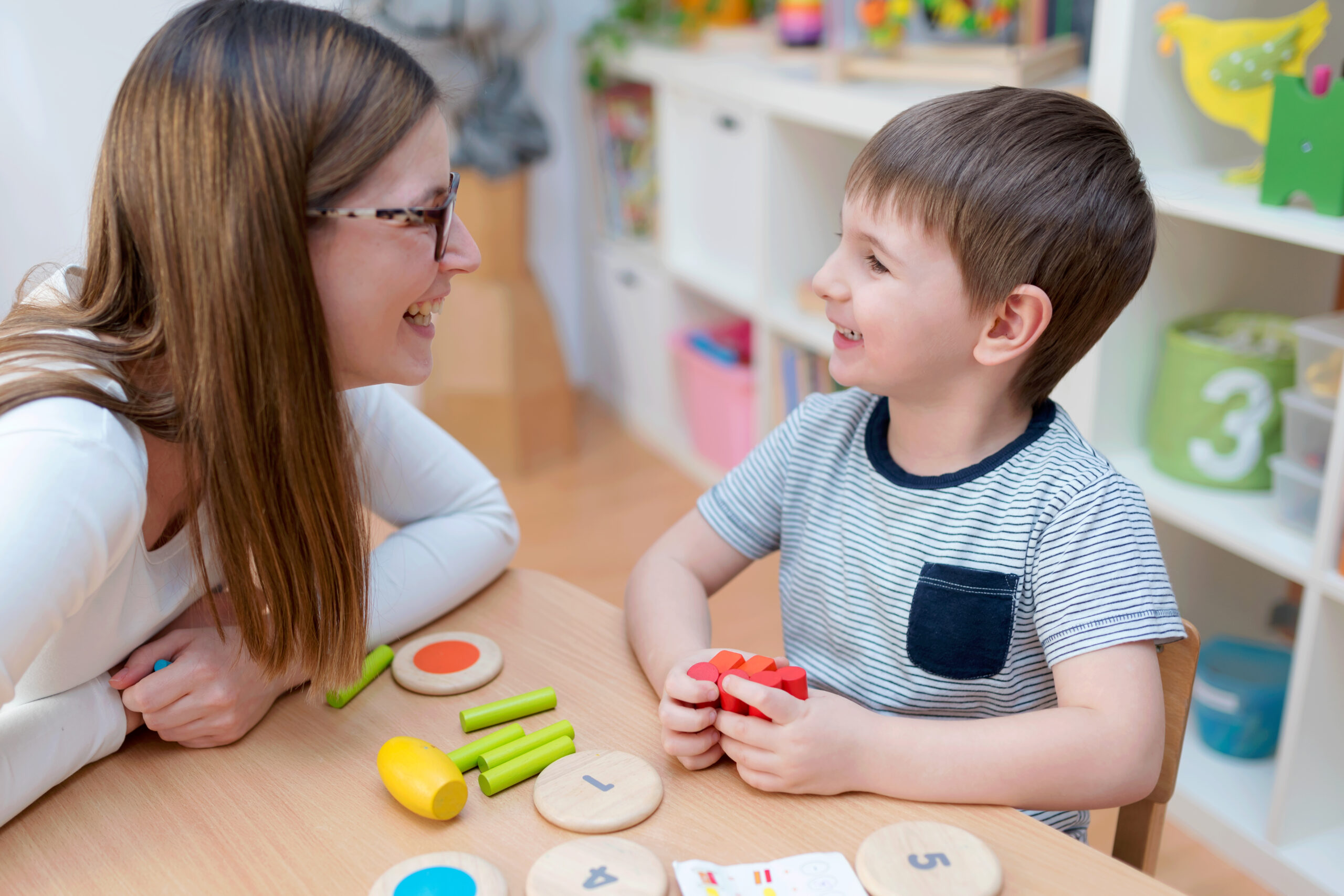 Proud mother looking at her son playing didactic games learning