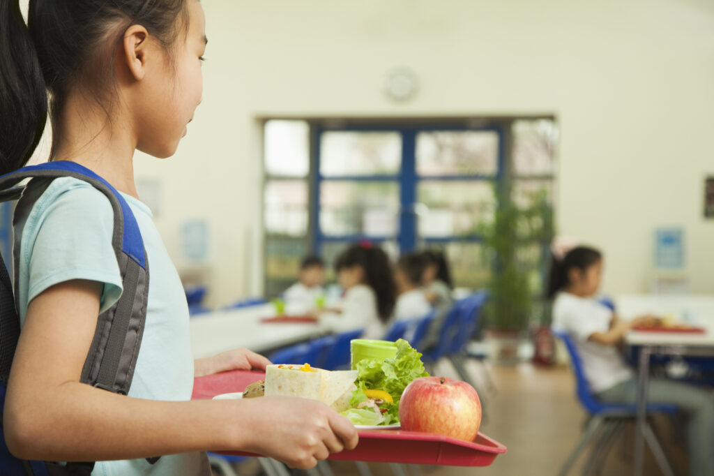 Girl holding food tray in school cafeteria